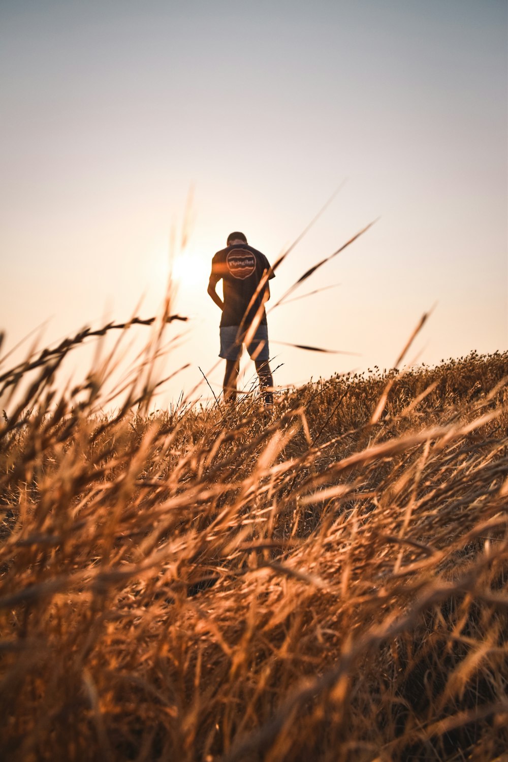 a man standing on top of a grass covered hill