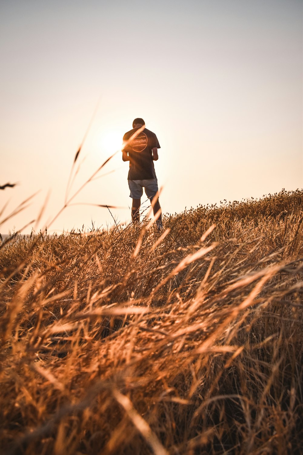 a man standing on top of a grass covered hillside