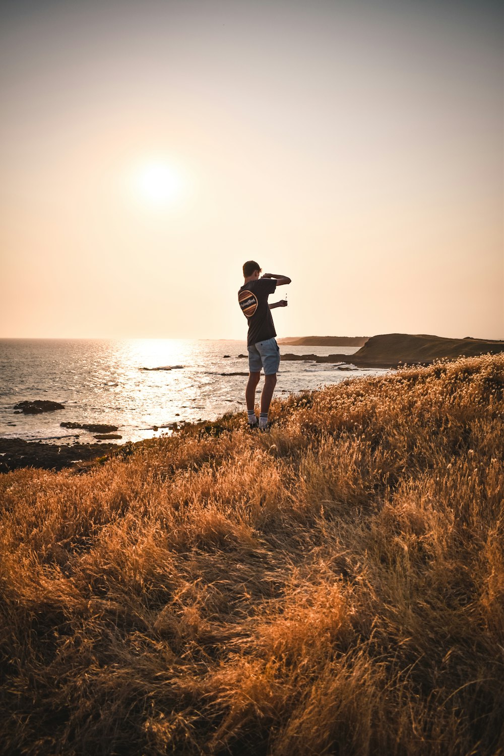 a man standing on top of a grass covered hillside