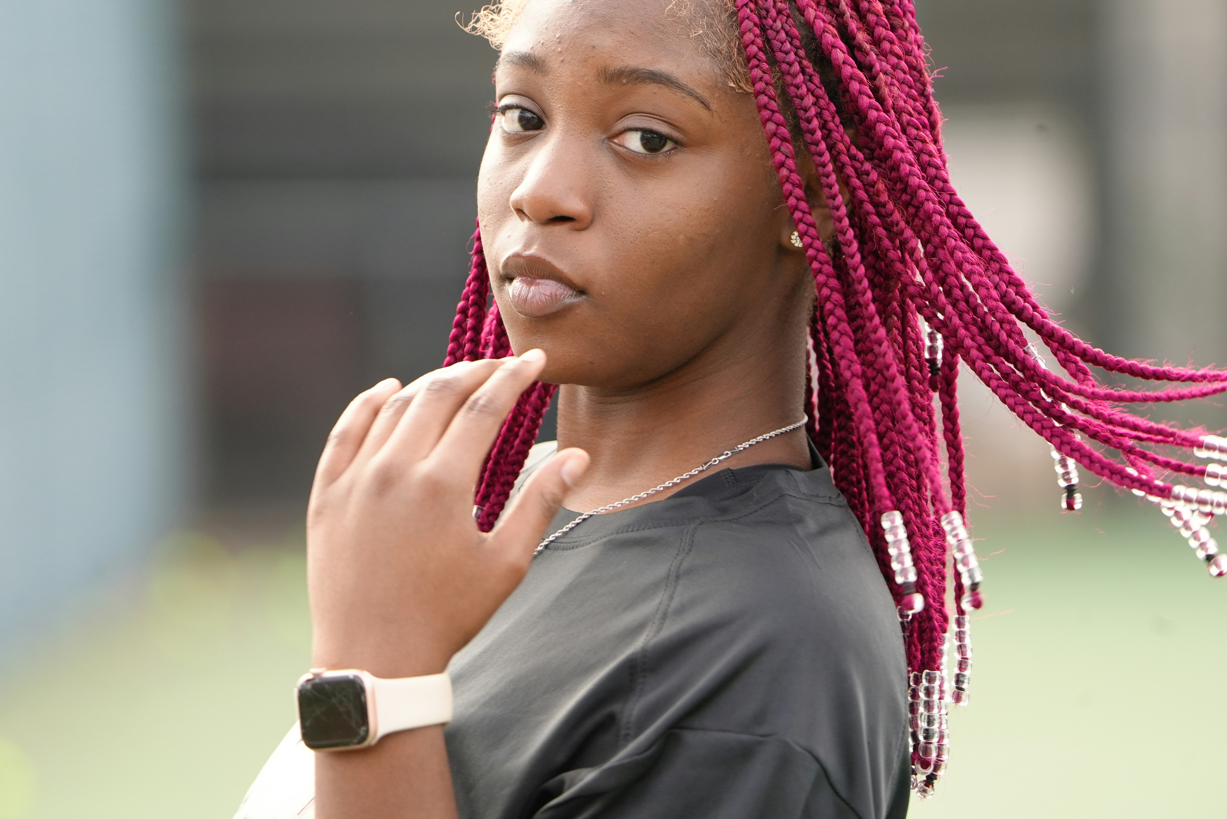 a woman with pink dreadlocks standing in front of a building