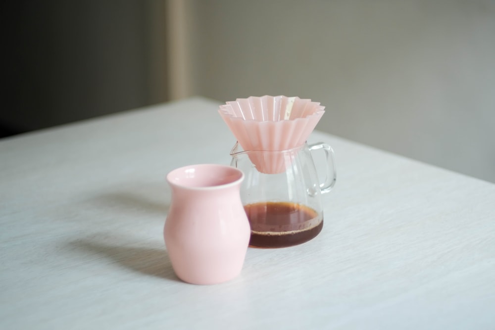 a pink vase and a pink cup sitting on a table