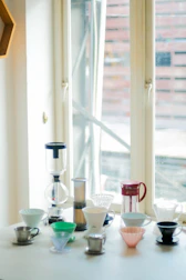 Various manual brew tools including V60, Kalita, and French press arranged on a wooden table.