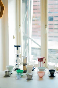 Various manual brew tools including V60, Kalita, and French press arranged on a wooden table.