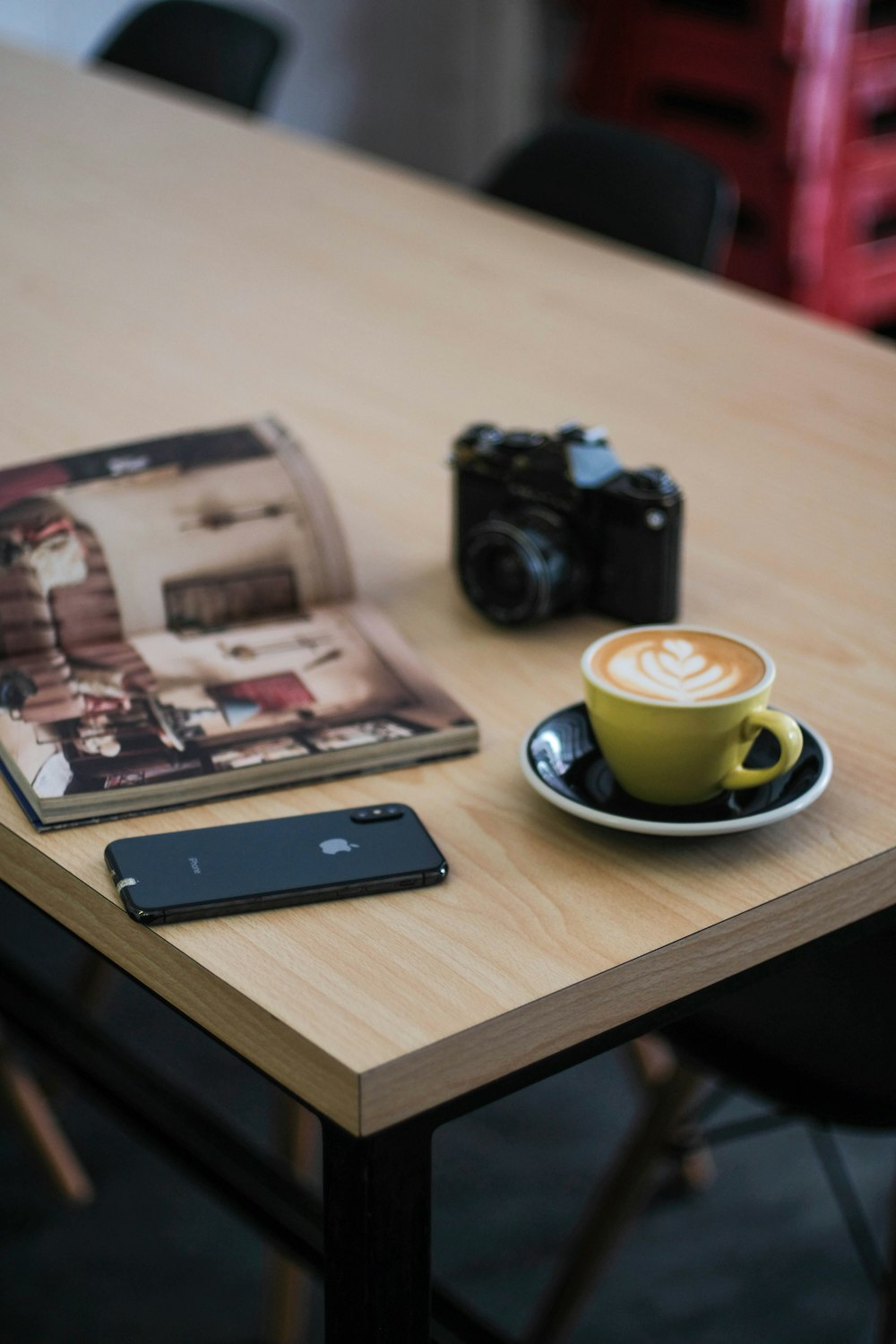 a table with a cup of coffee, cell phone and camera