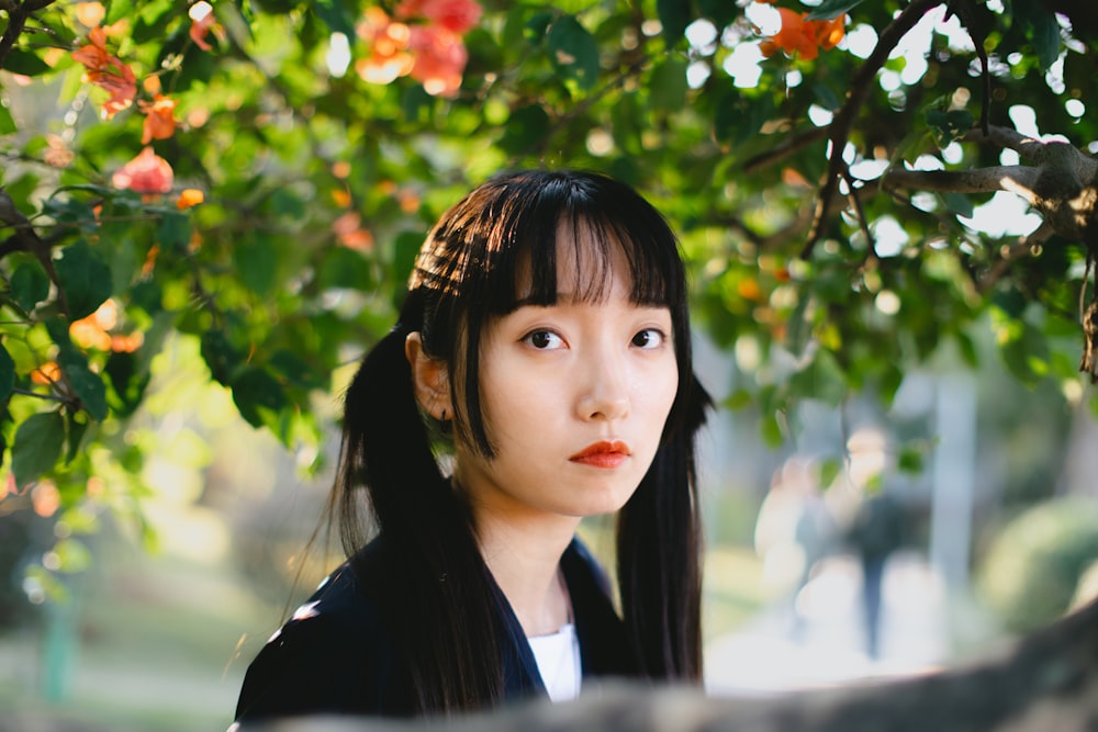 a young woman standing under a tree looking at the camera