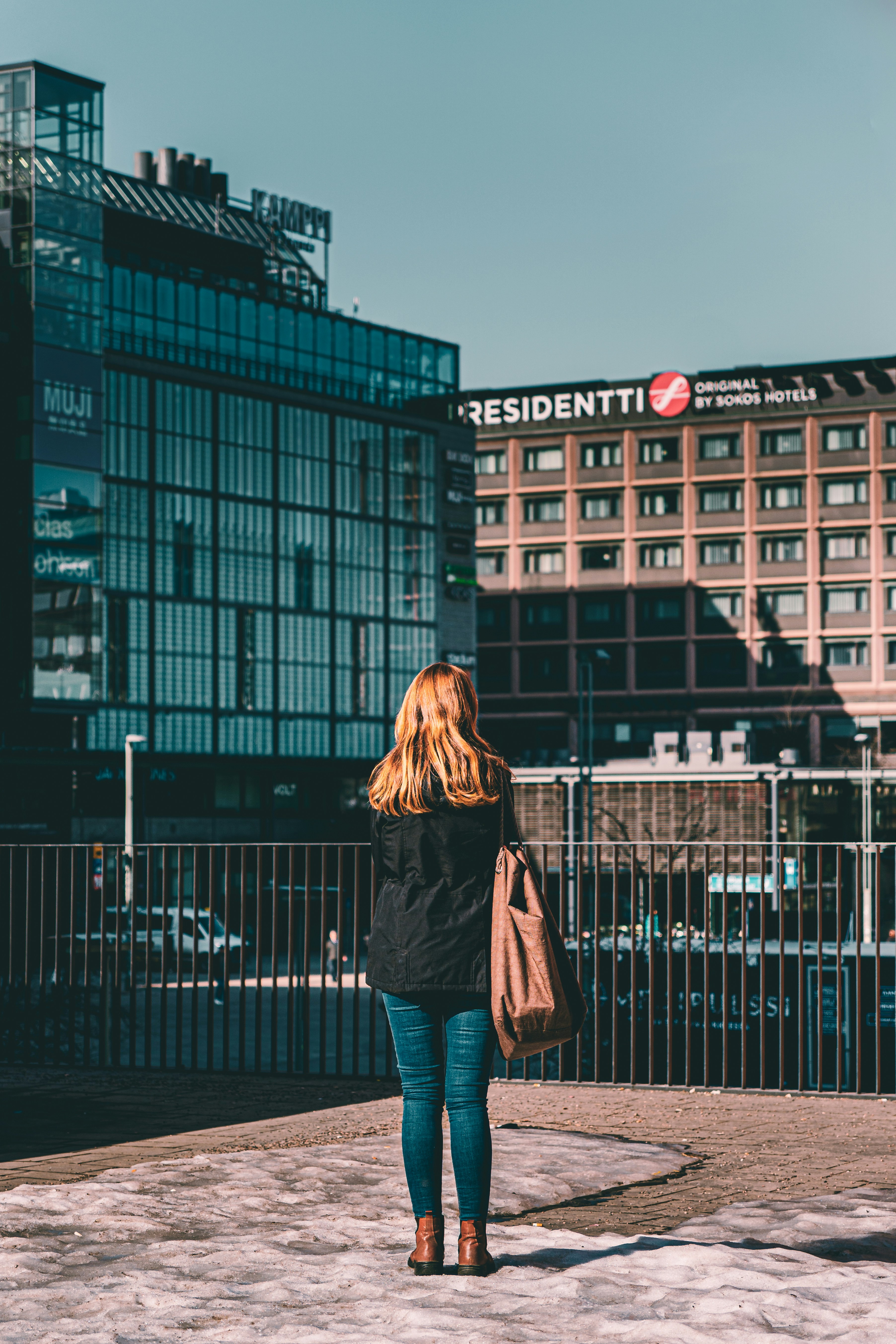 a woman walking down a sidewalk in front of a building