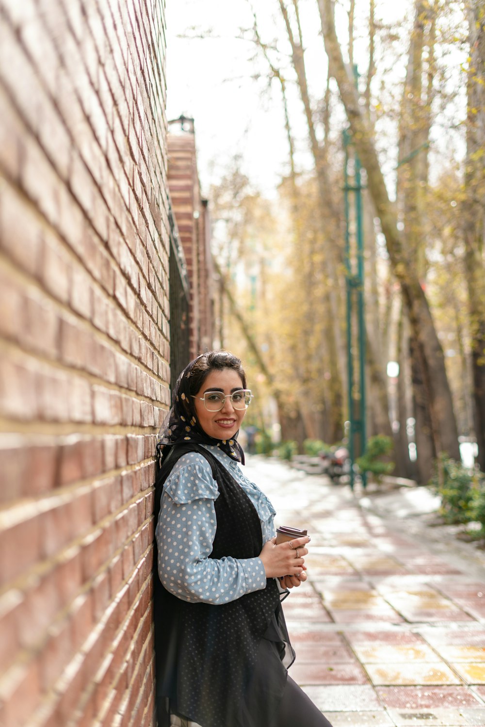 a woman leaning up against a brick wall