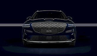 the front end of a blue car in a dark room