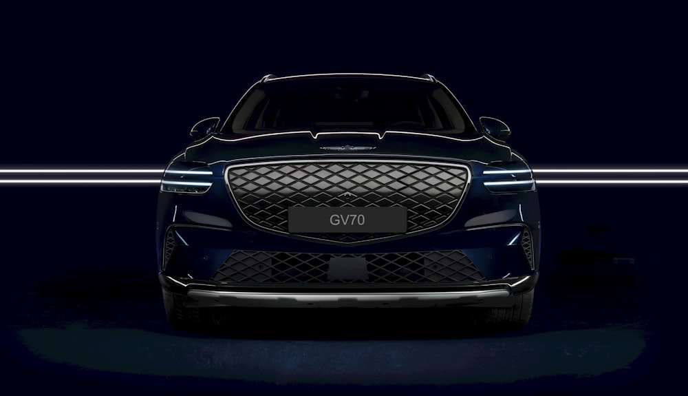 the front end of a blue car in a dark room