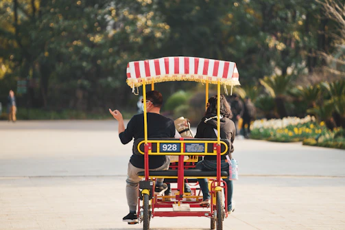 Elderly couple happily riding electric tricycles along a park path.