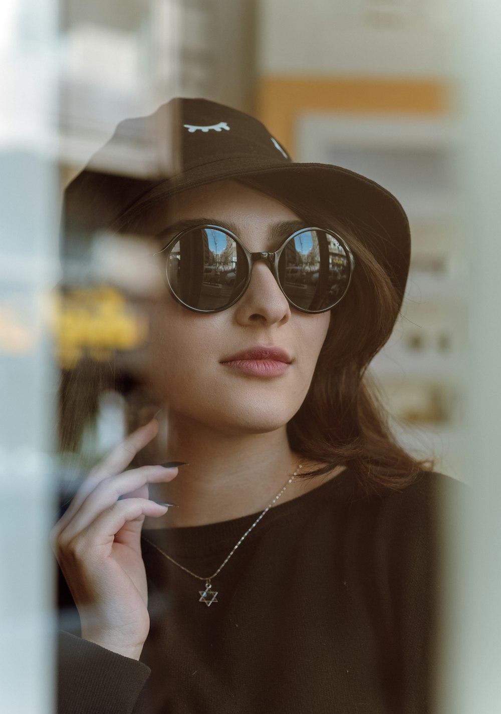 a woman in a hat and sunglasses smoking a cigarette