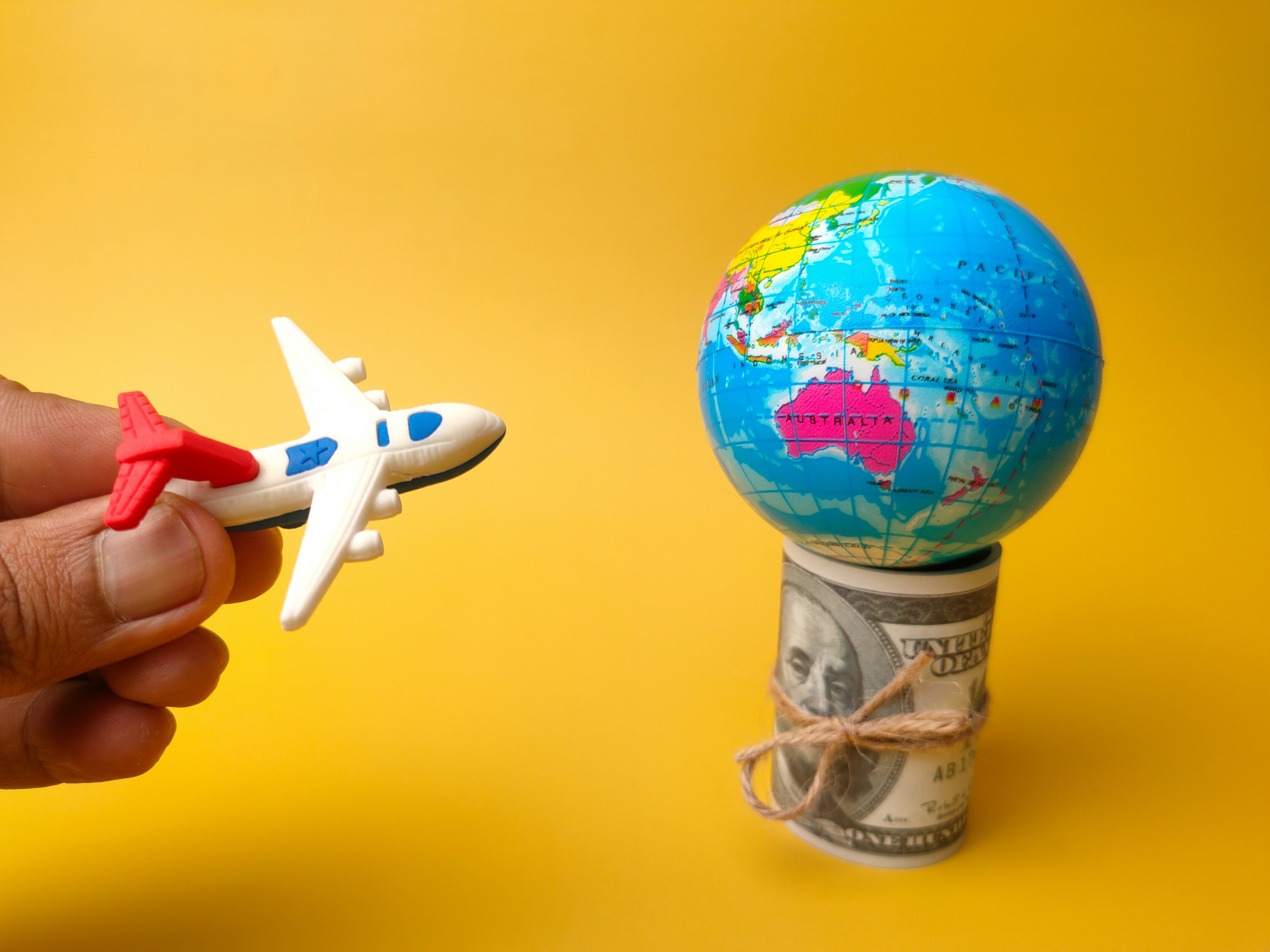 banknotes, earth globe and airplane on yellow background.