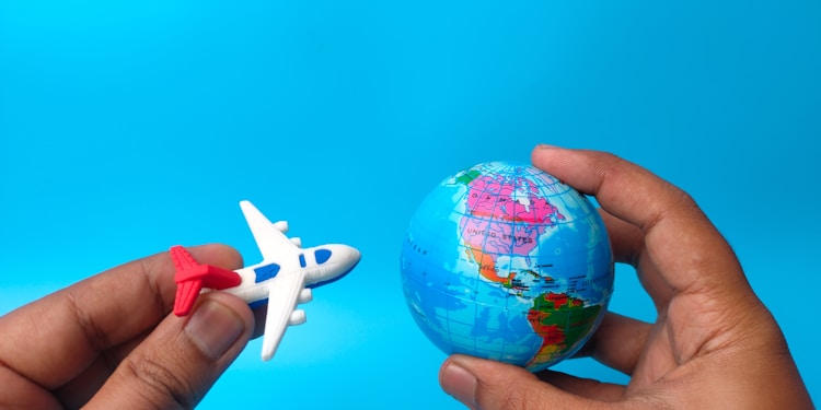 Hand holding earth globe and airplane on blue background.
