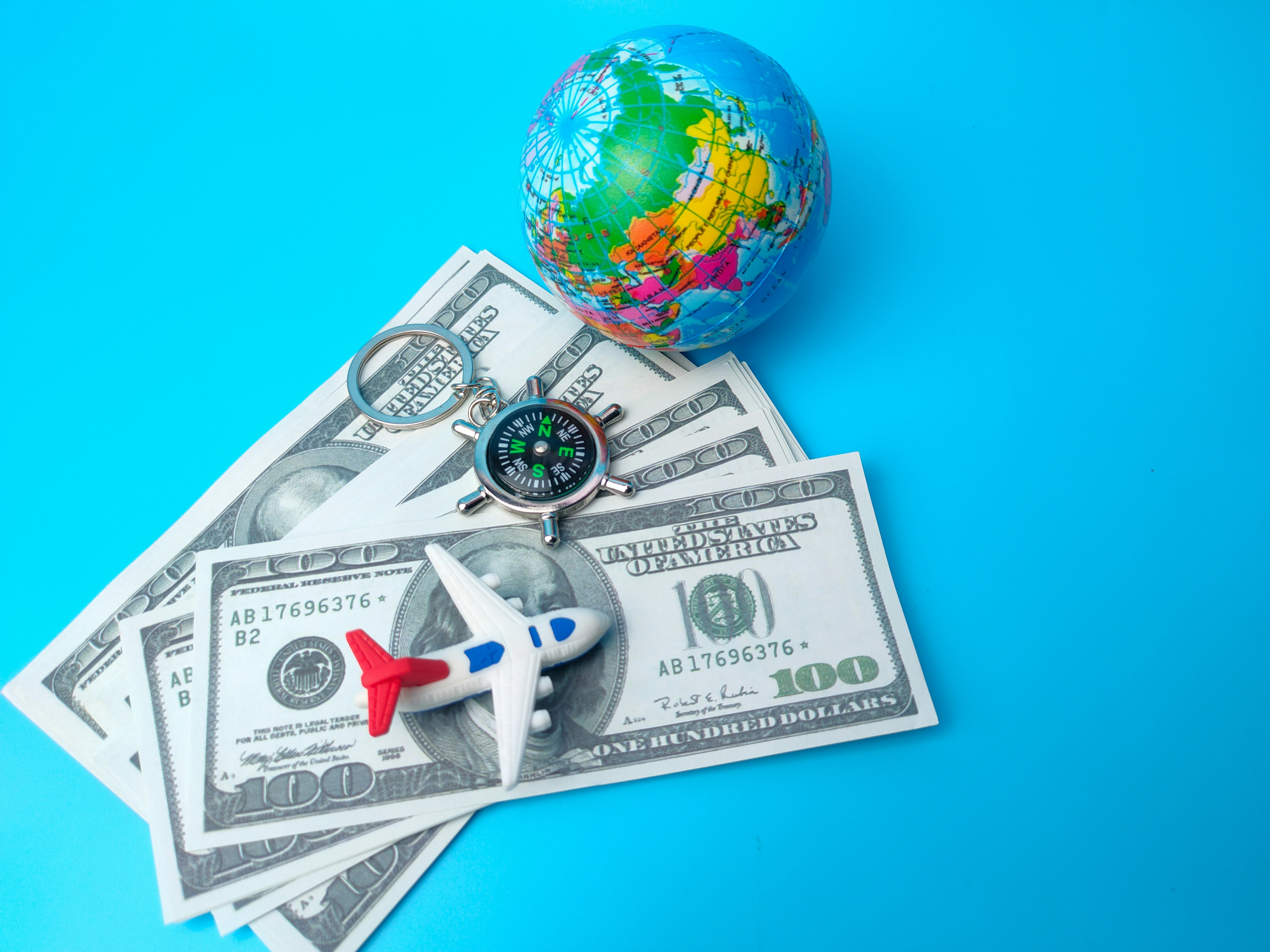 Compass,banknotes, earth globe and airplane on blue background.