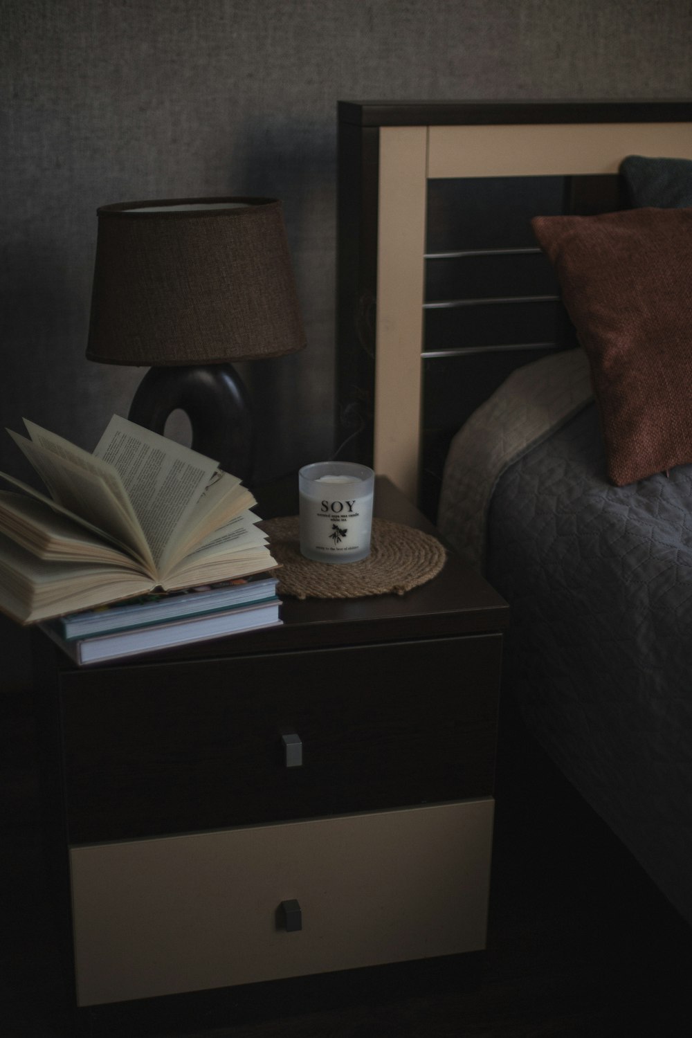 a nightstand with a book and a cup of coffee on it