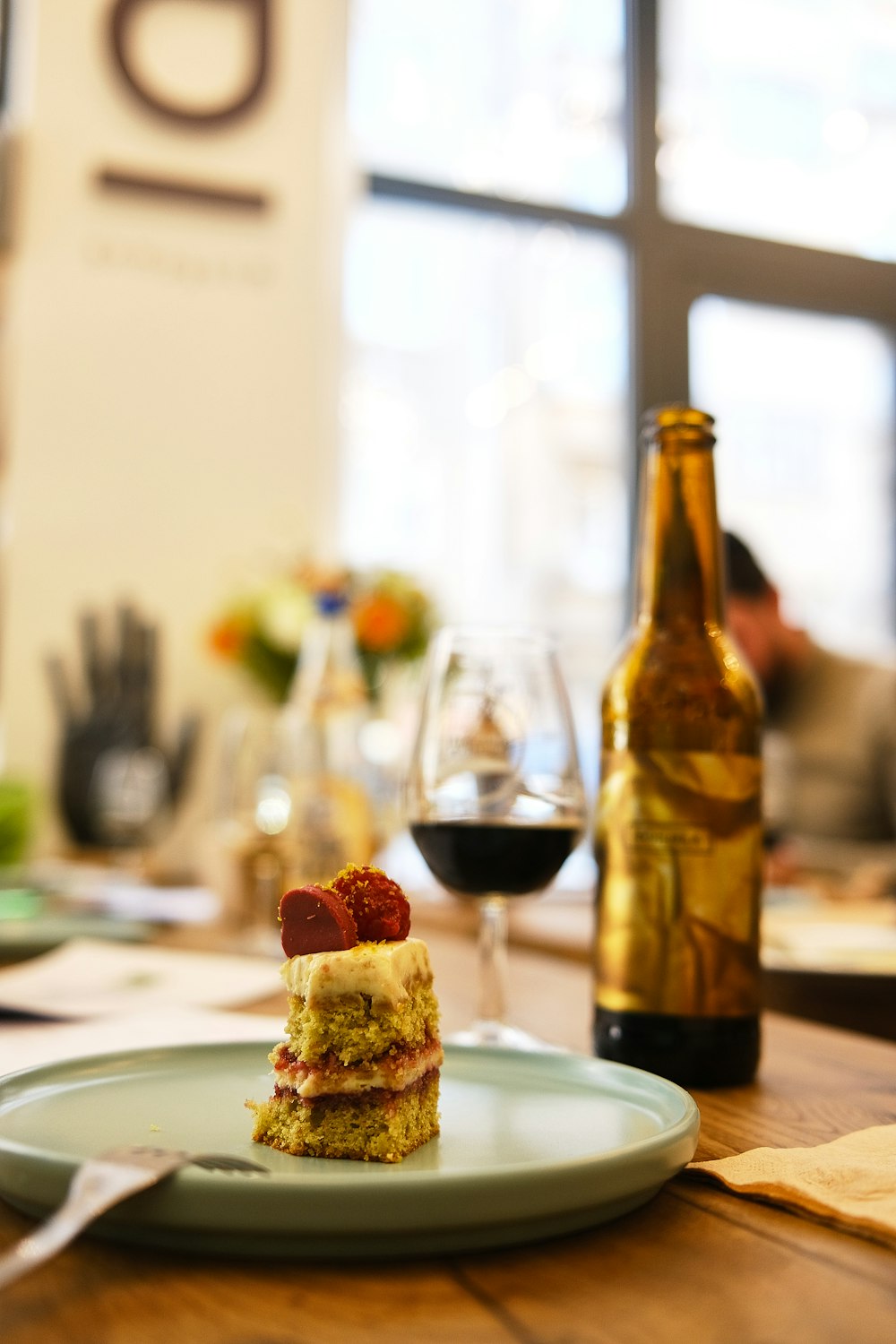 a piece of cake sitting on a plate next to a bottle of wine