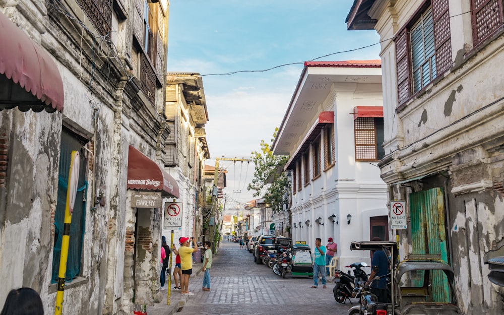 a narrow street lined with parked motorcycles and people