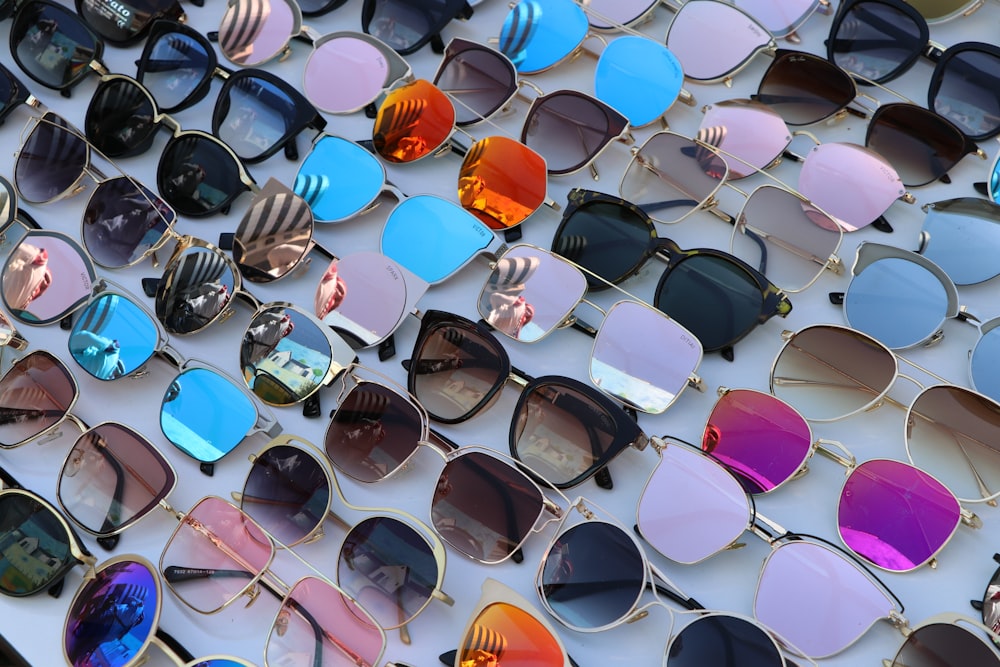 many different colored sunglasses are lined up on a wall