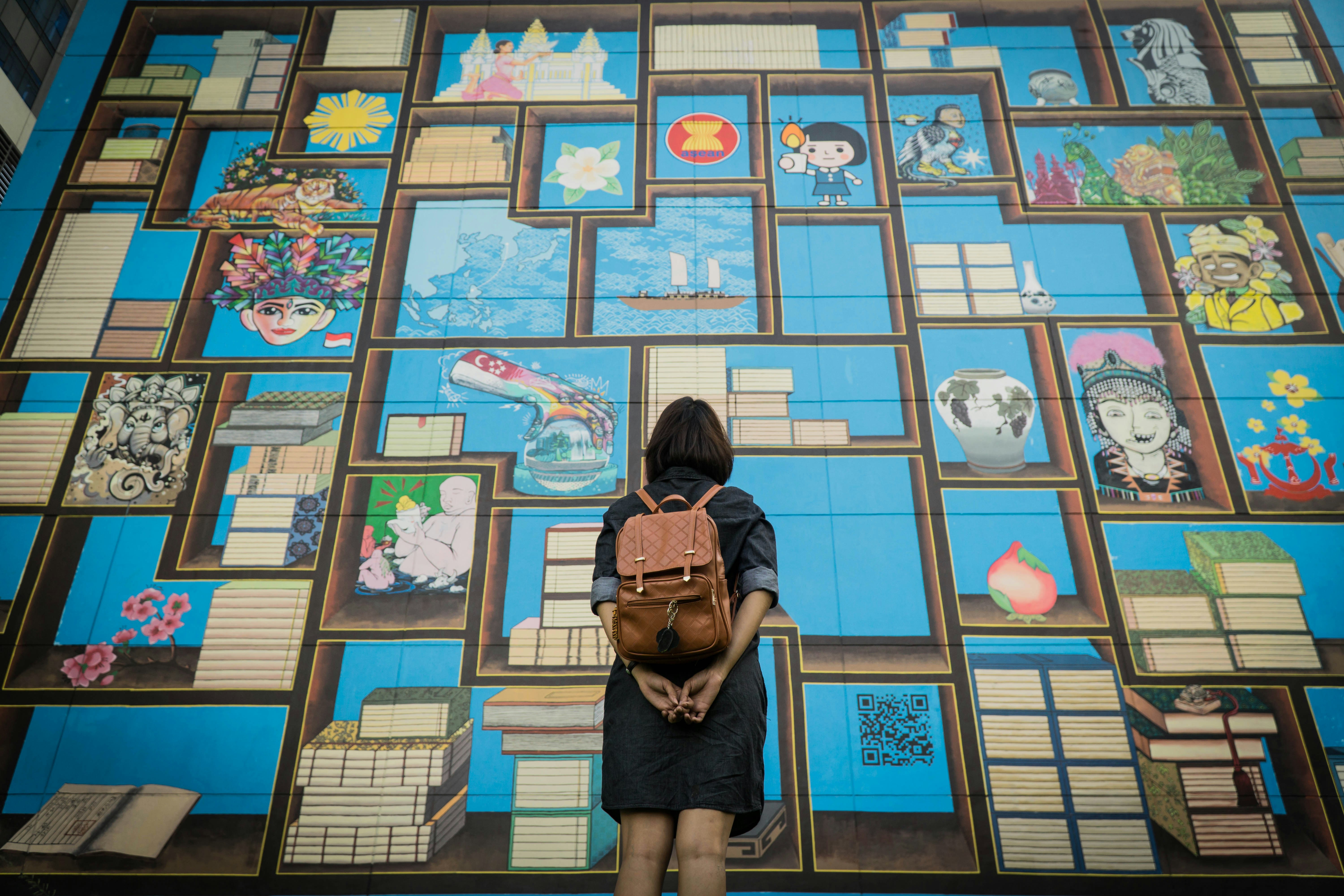 a woman with a backpack standing in front of a mural