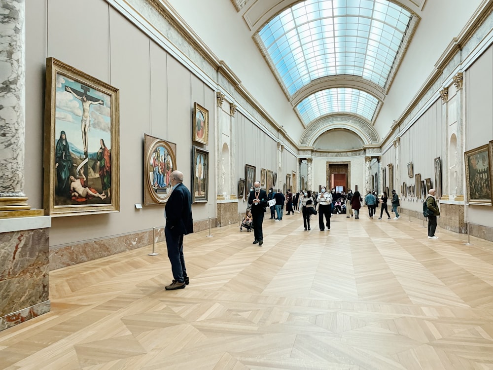 a group of people standing in a room with paintings on the walls