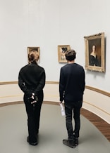 a man and woman looking at paintings in a museum