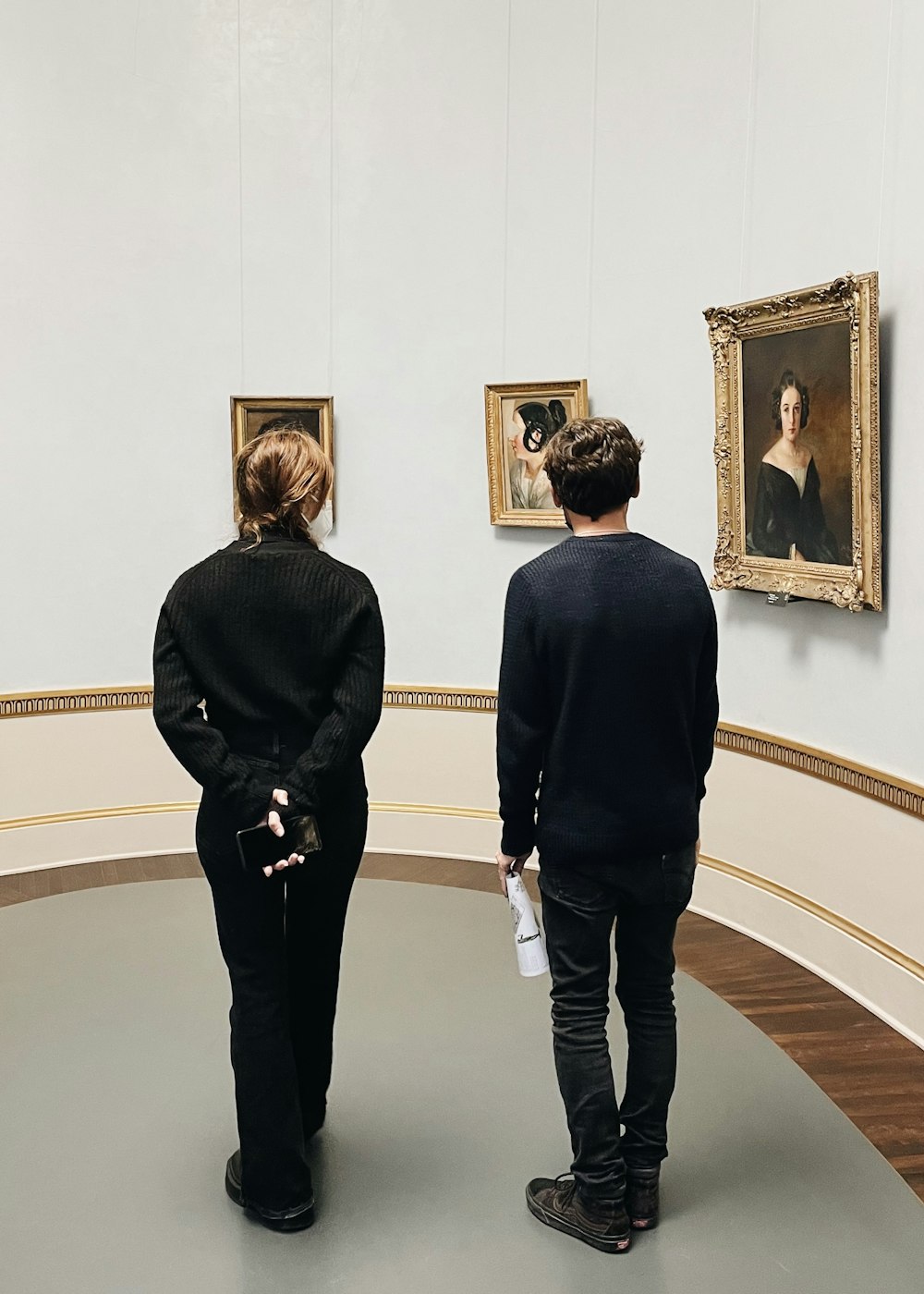 a man and woman looking at paintings in a museum