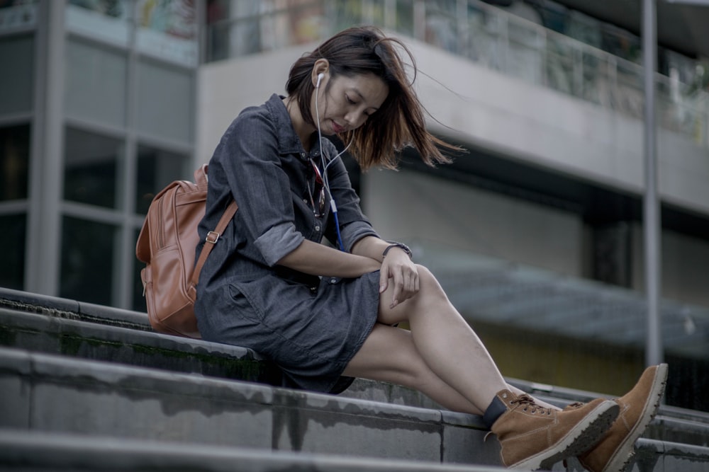 a woman sitting on a ledge using her cell phone