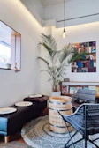 A cozy coffee shop corner decorated with palm leaf artwork and colorful Dominican textiles, inviting visitors to relax.