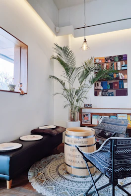 A cozy coffee shop corner decorated with palm leaf artwork and colorful Dominican textiles, inviting visitors to relax.