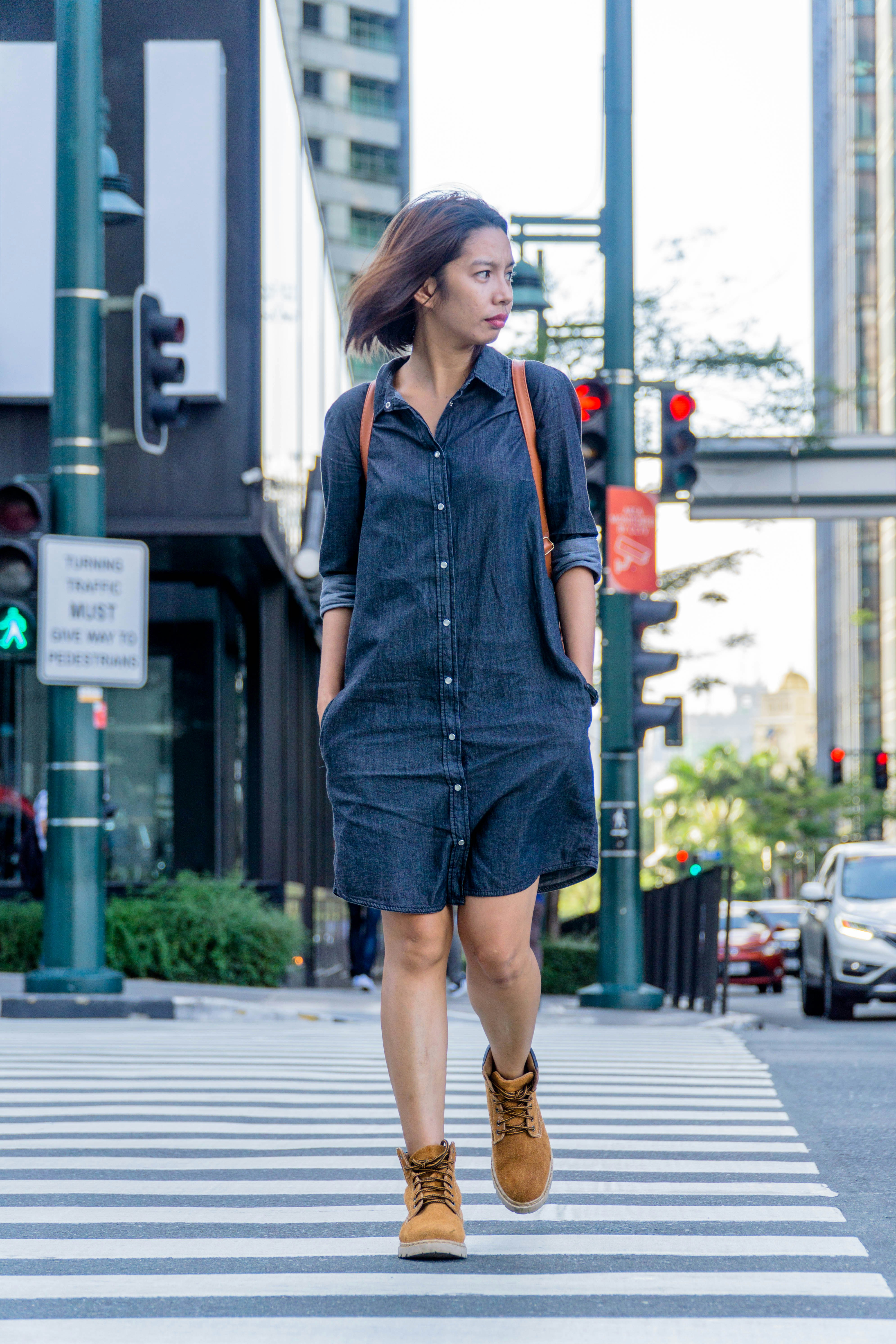 a woman walking across a cross walk in a city