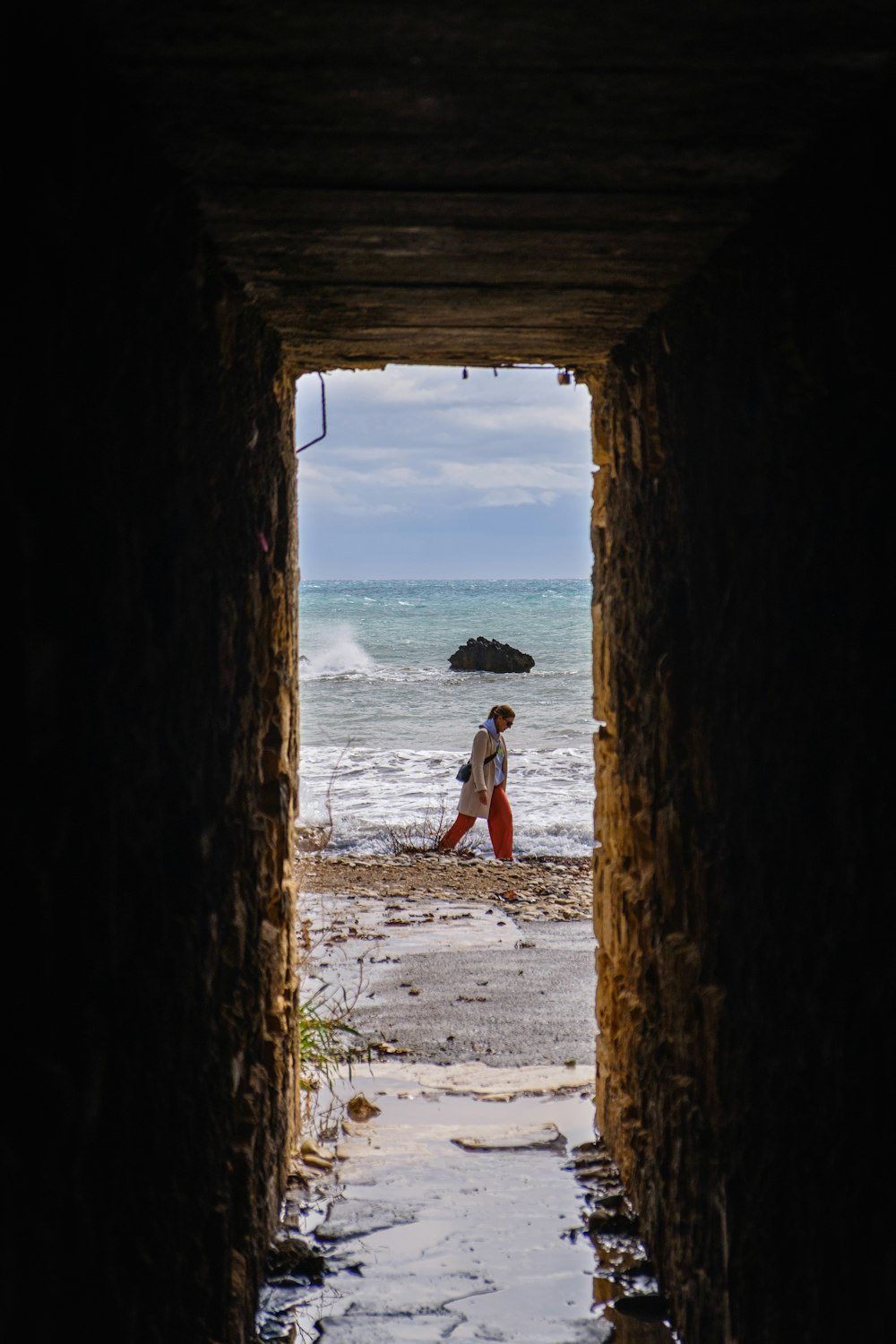 a man walking through a tunnel into the ocean
