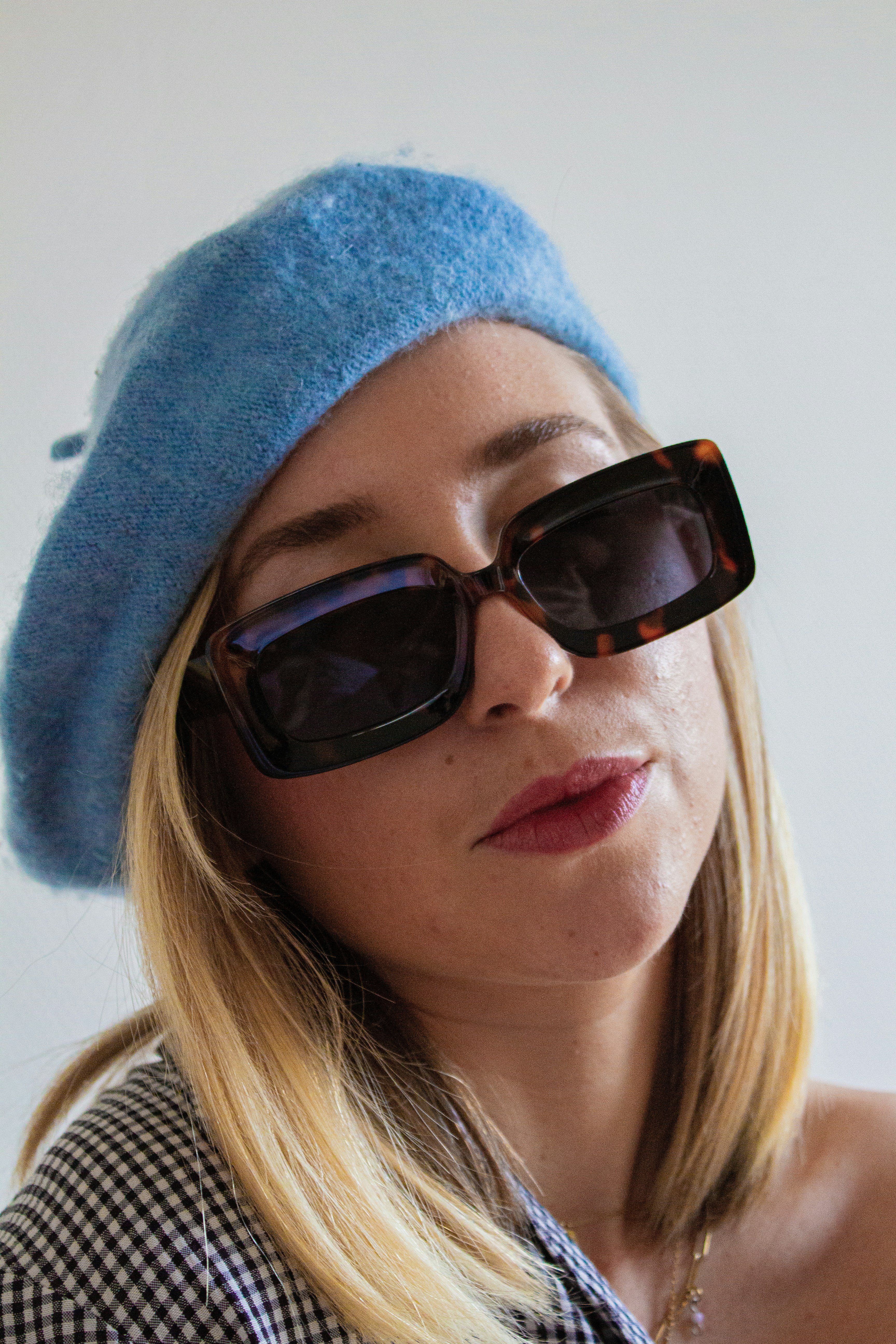 Eine Frau mit blauem Hut und Sonnenbrille