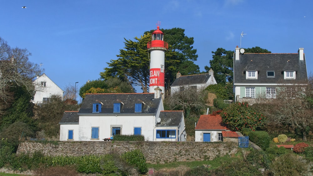 a lighthouse on top of a hill with houses around it