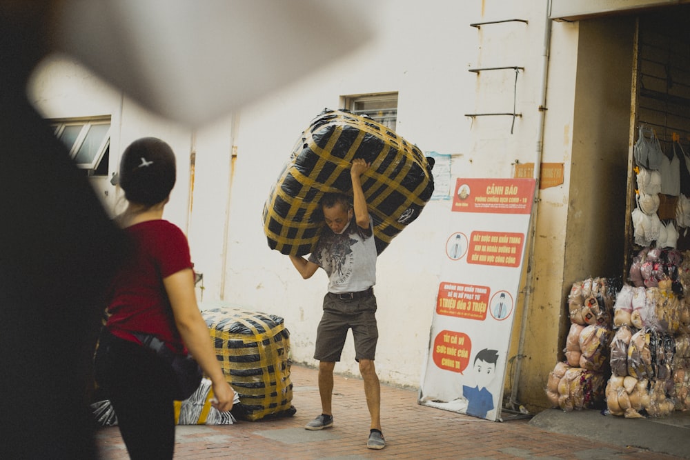 a man carrying a large amount of luggage down a street