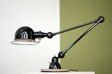 Modern black and gold desk lamp casting warm light on a stylish workspace.