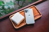 Compact power bank resting on a wooden desk beside a smartphone.