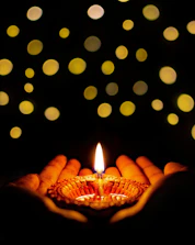 Soft candlelight illuminating a circle of women holding hands in a cozy room.