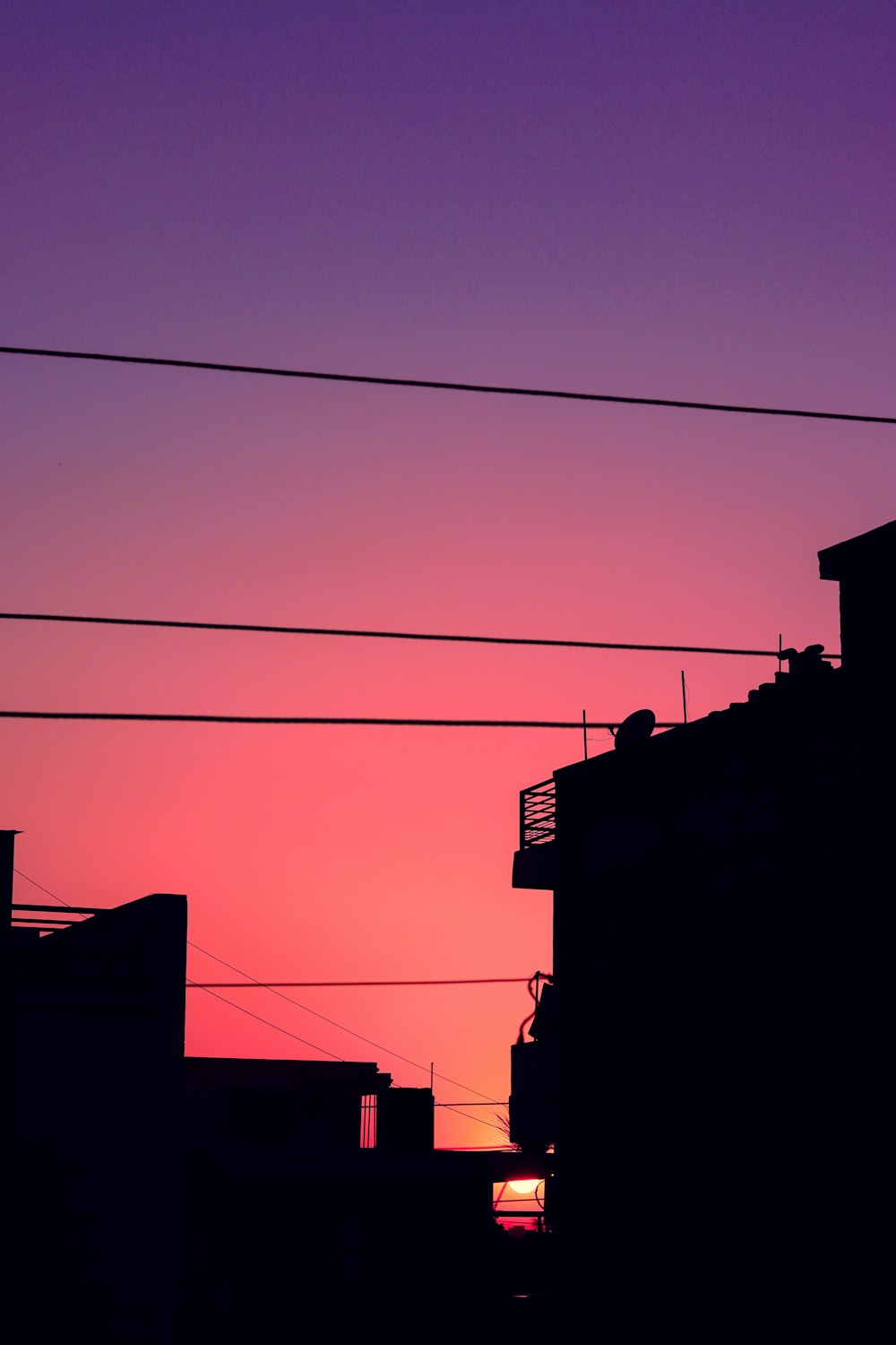 the sun is setting behind a building with power lines in the foreground