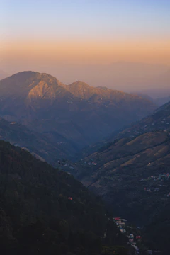 Sunset view over a mountain range with a small group gathered around a campfire.