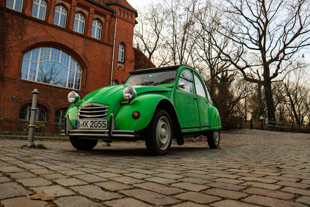 a green car parked in front of a brick building
