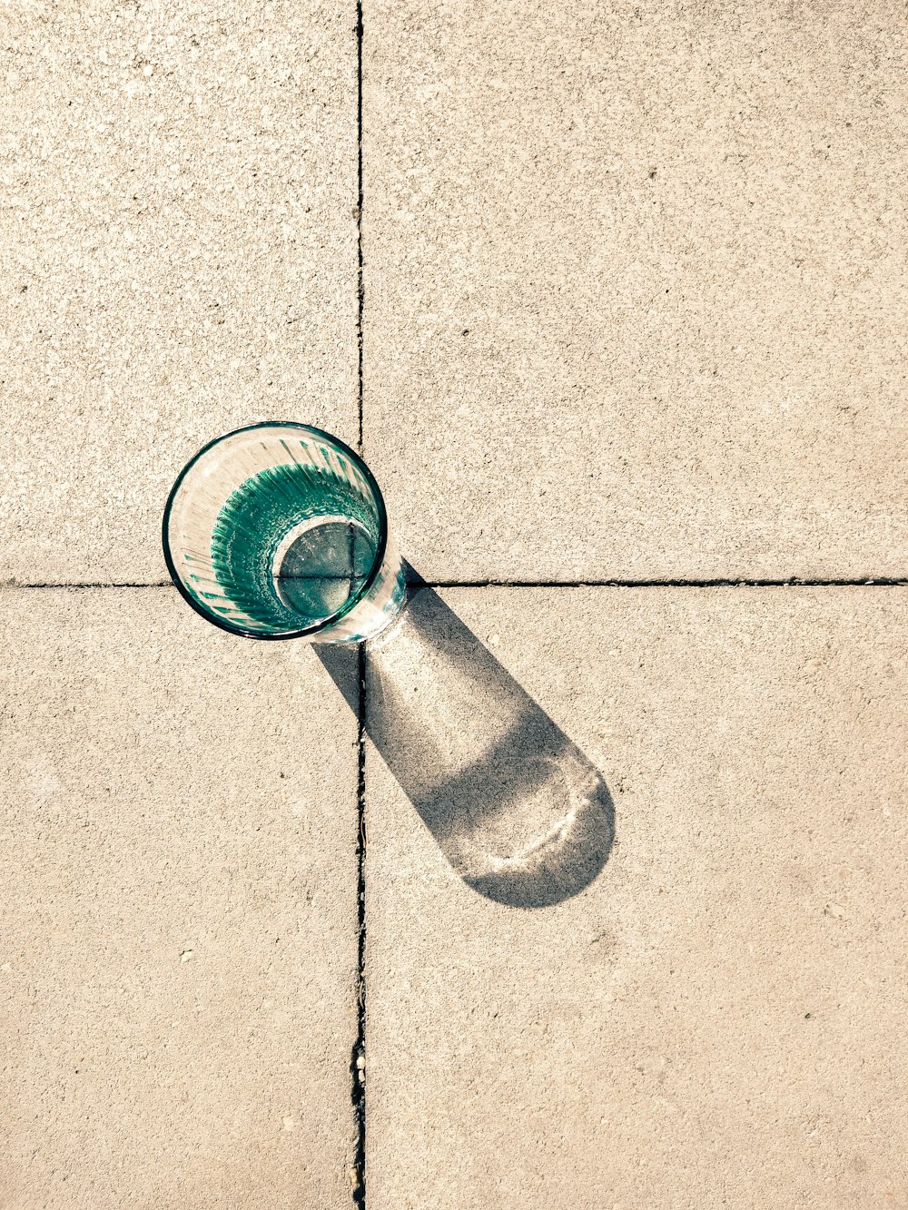 a glass sitting on the ground on a sidewalk