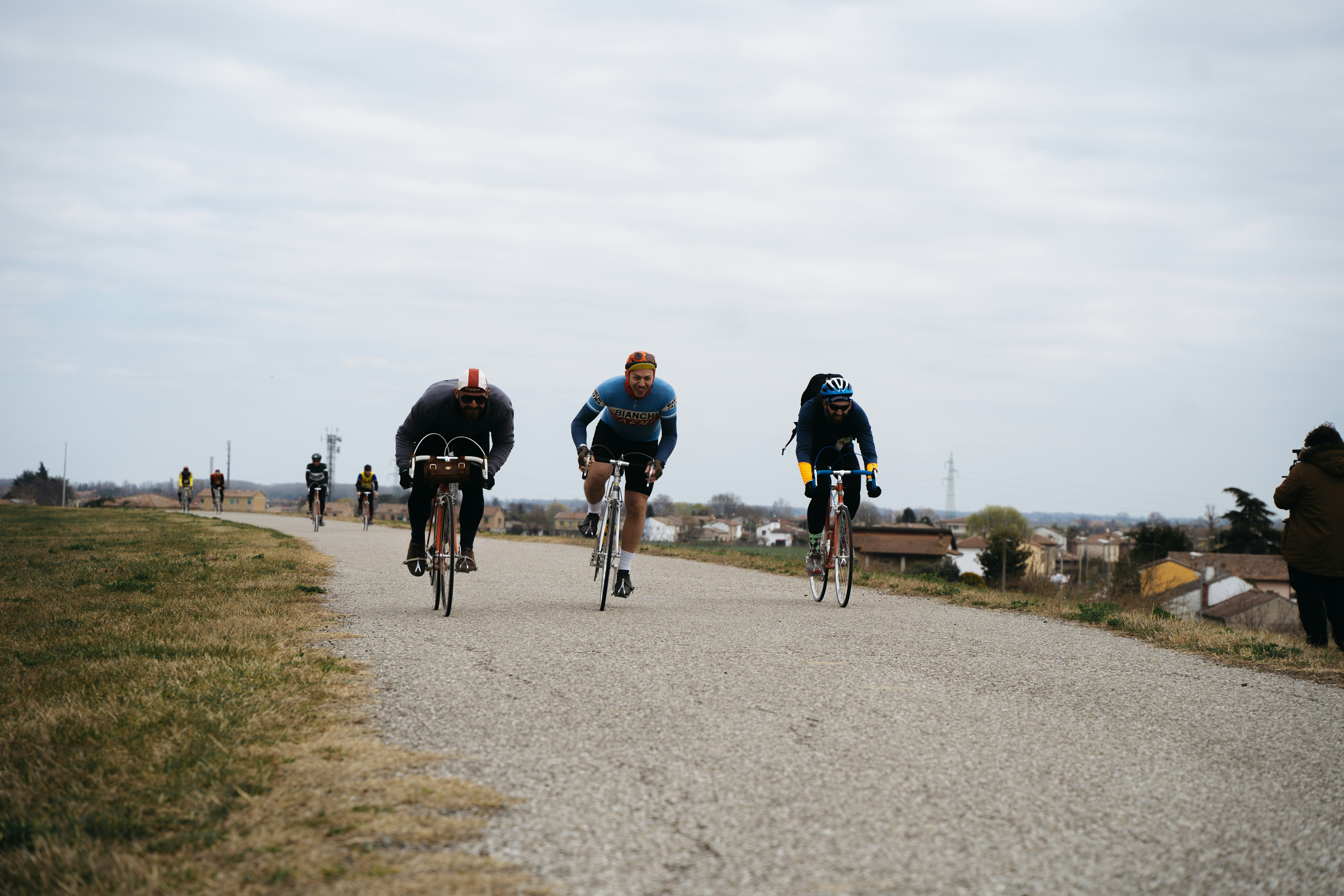 a group of bicyclists riding down a gravel road