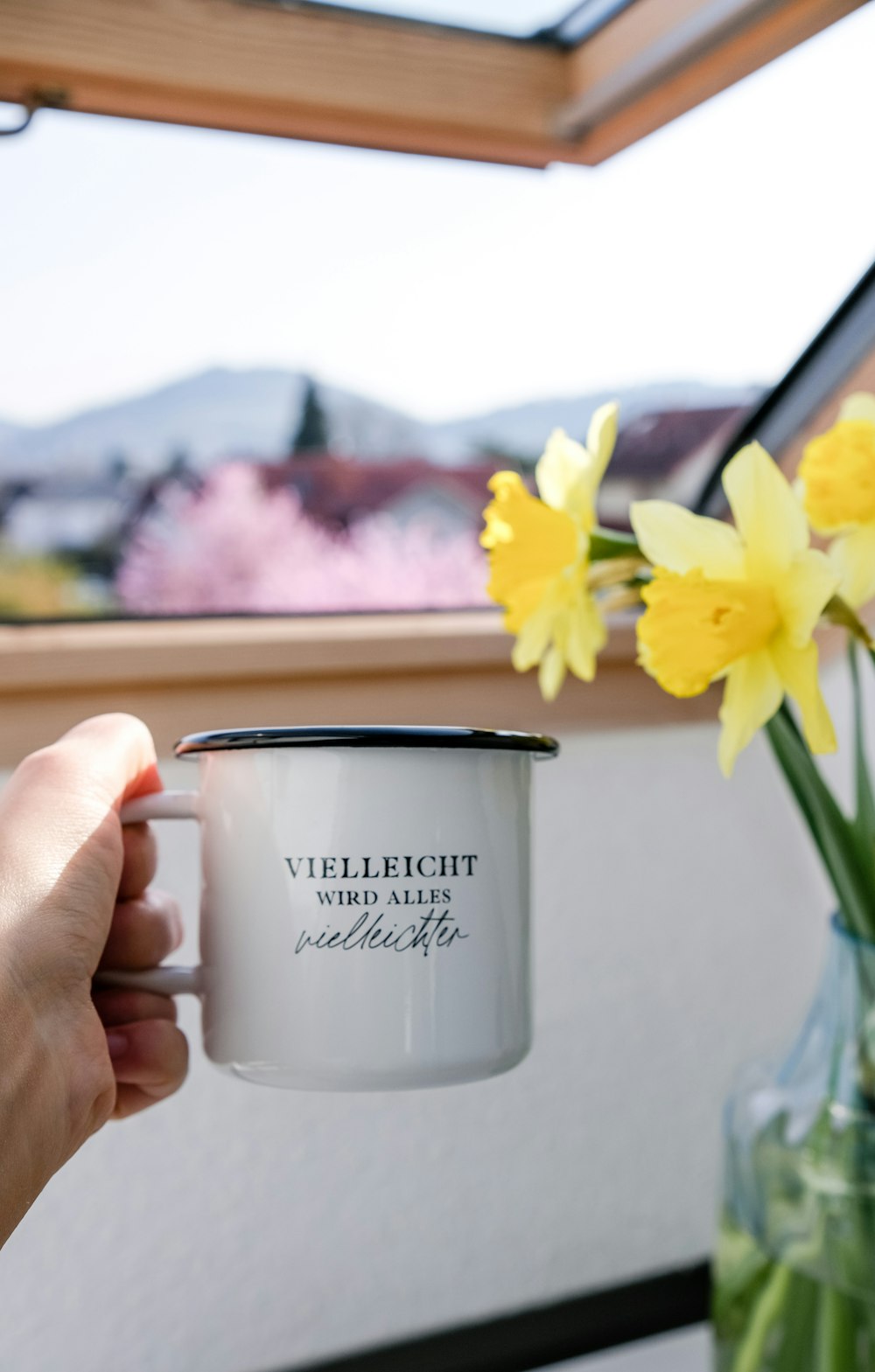 a cup of coffee and a vase of flowers on a table