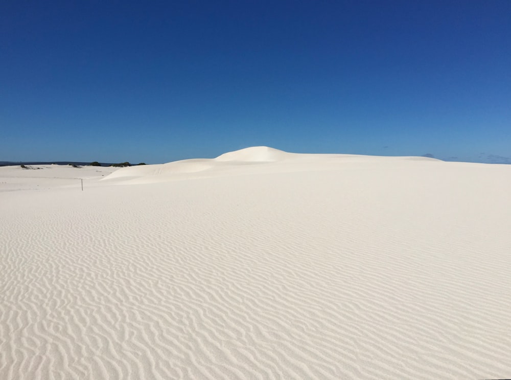 Una duna de arena blanca con un cielo azul al fondo