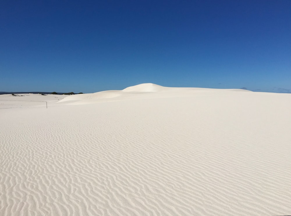 a white sand dune with a blue sky in the background