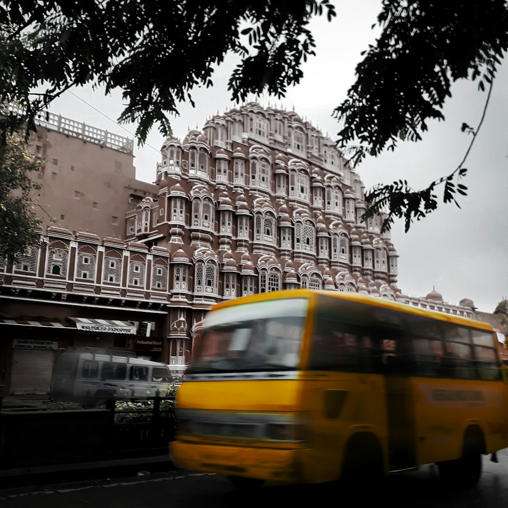 a yellow bus driving down a street next to a tall building