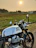 Man riding a Royal Enfield Classic 350 along the coastline near Jagannath Temple at sunset.