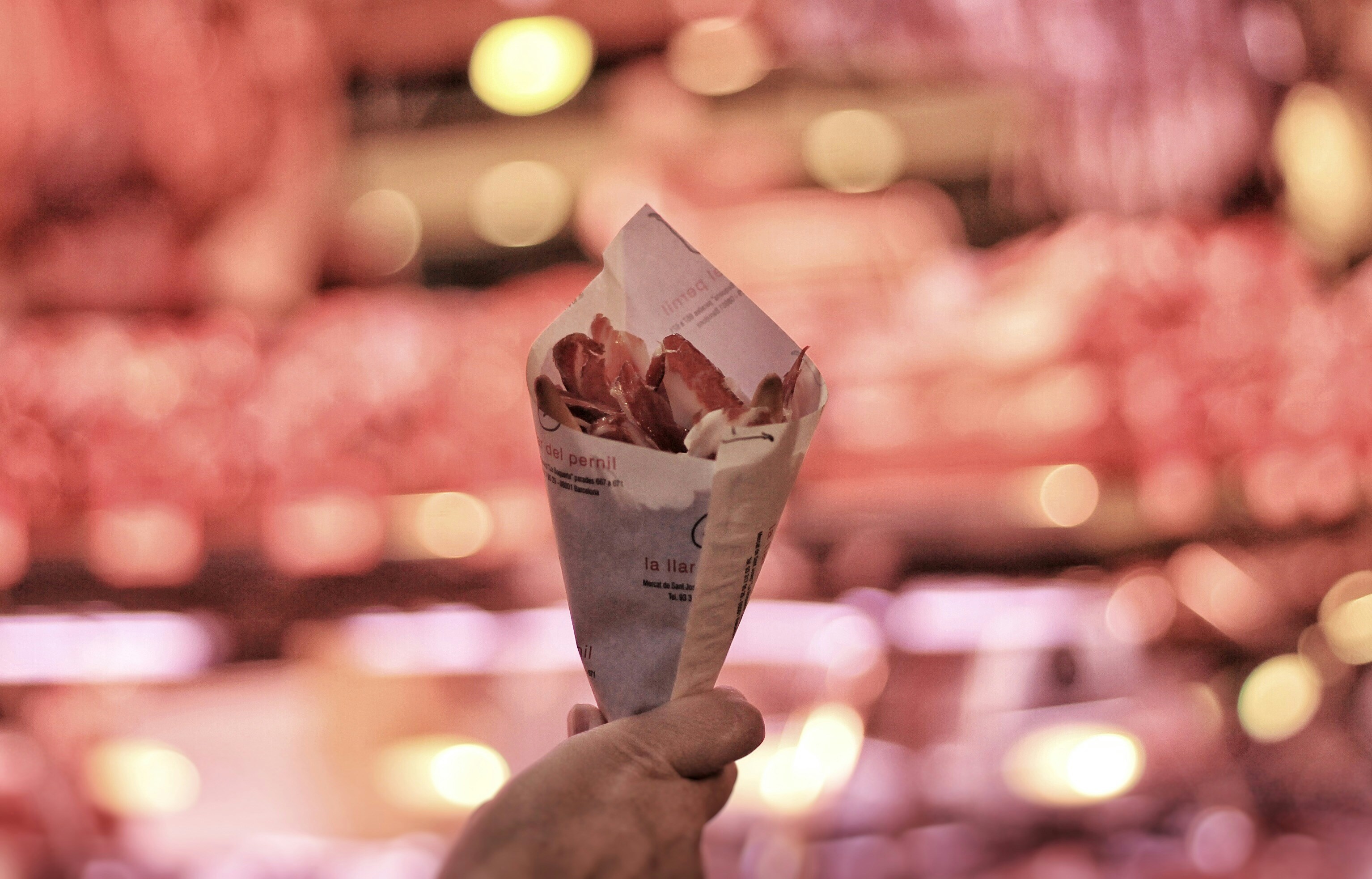 a person holding up a paper cone filled with food, Food in Mercat de la Boqueria