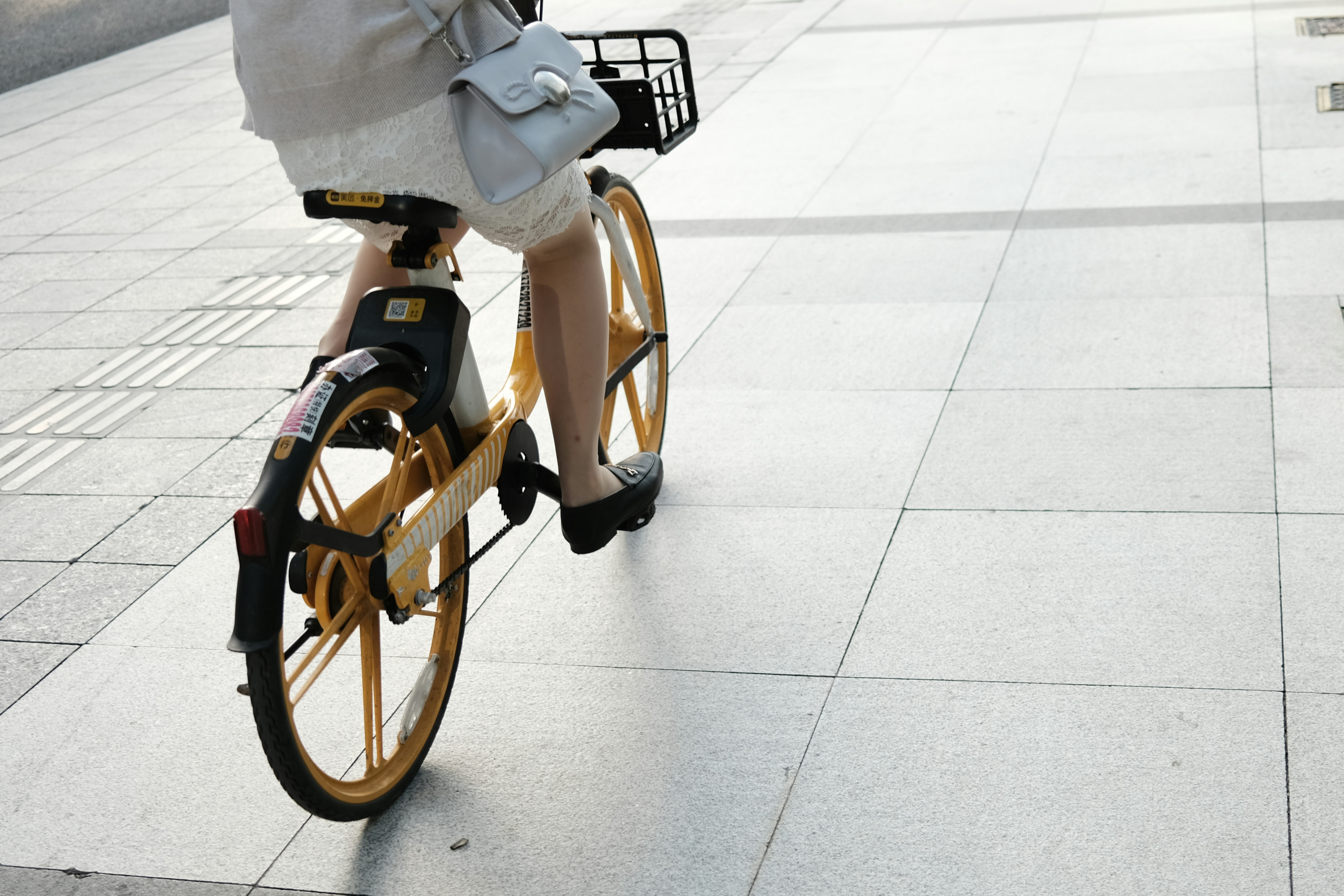 a woman riding a bike down a sidewalk