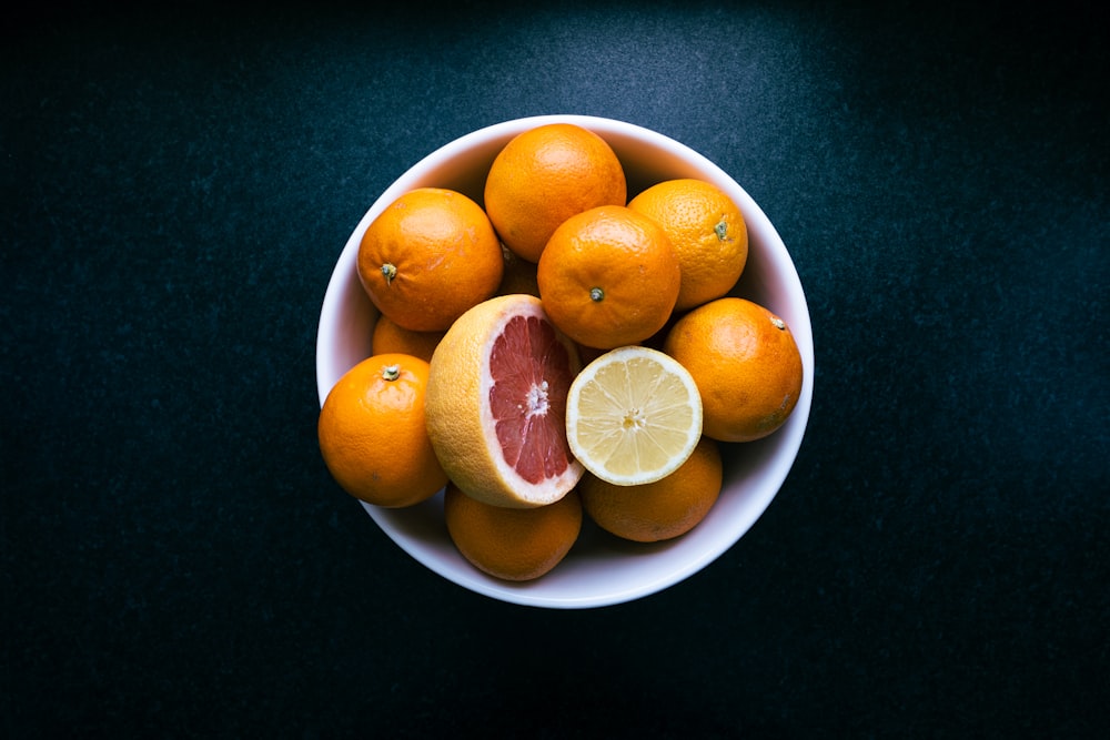 a bowl of oranges and a grapefruit on a table